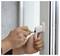 Eine Person verriegelt einen weißen Fenstergriff mit einem Schlüssel und legt dabei Wert auf Sicherheit.