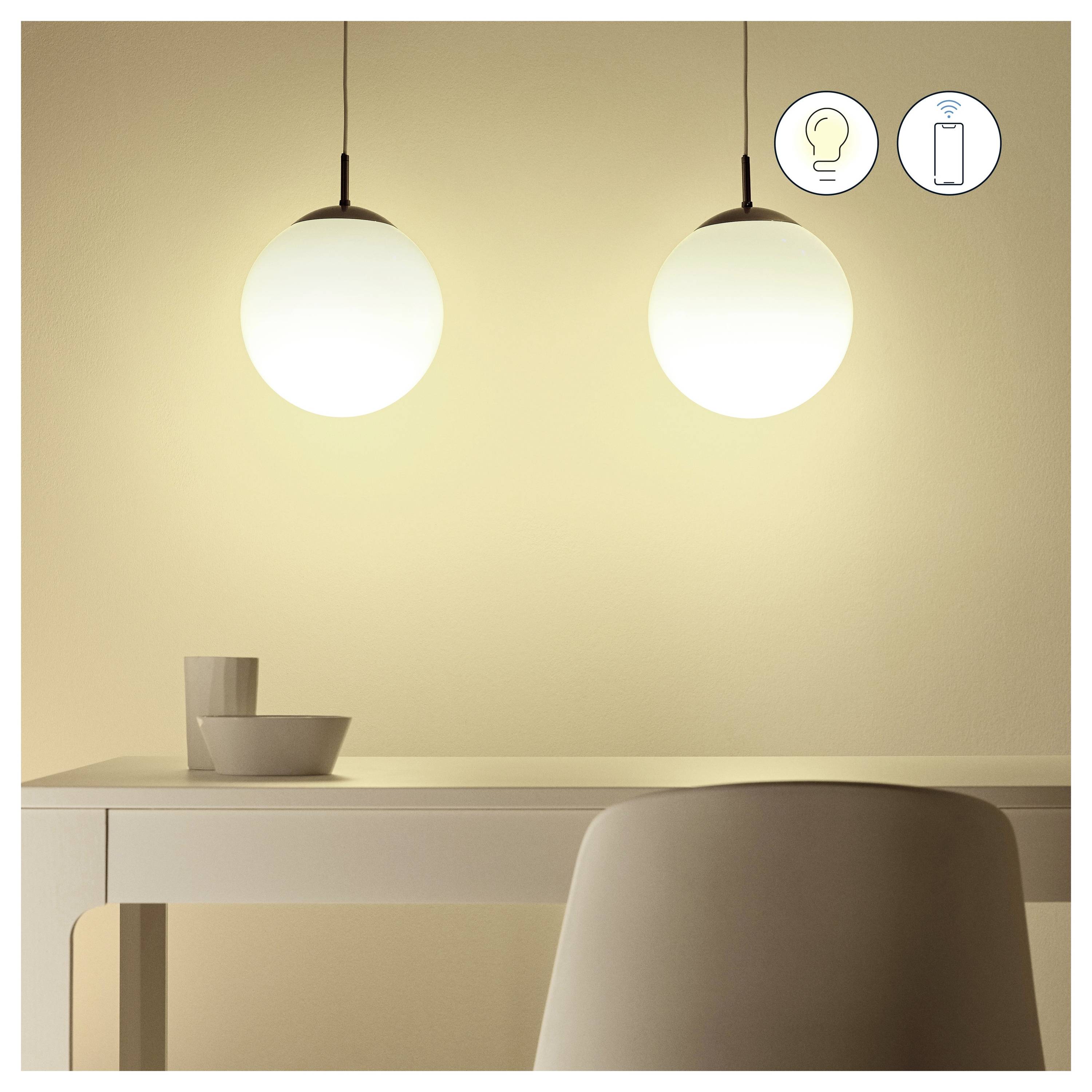 Zwei kugelförmige Pendelleuchten beleuchten einen minimalistischen Essbereich mit einem weißen Tisch, Stuhl und Geschirr. Symbole deuten auf eine intelligente Lichtsteuerung hin.
