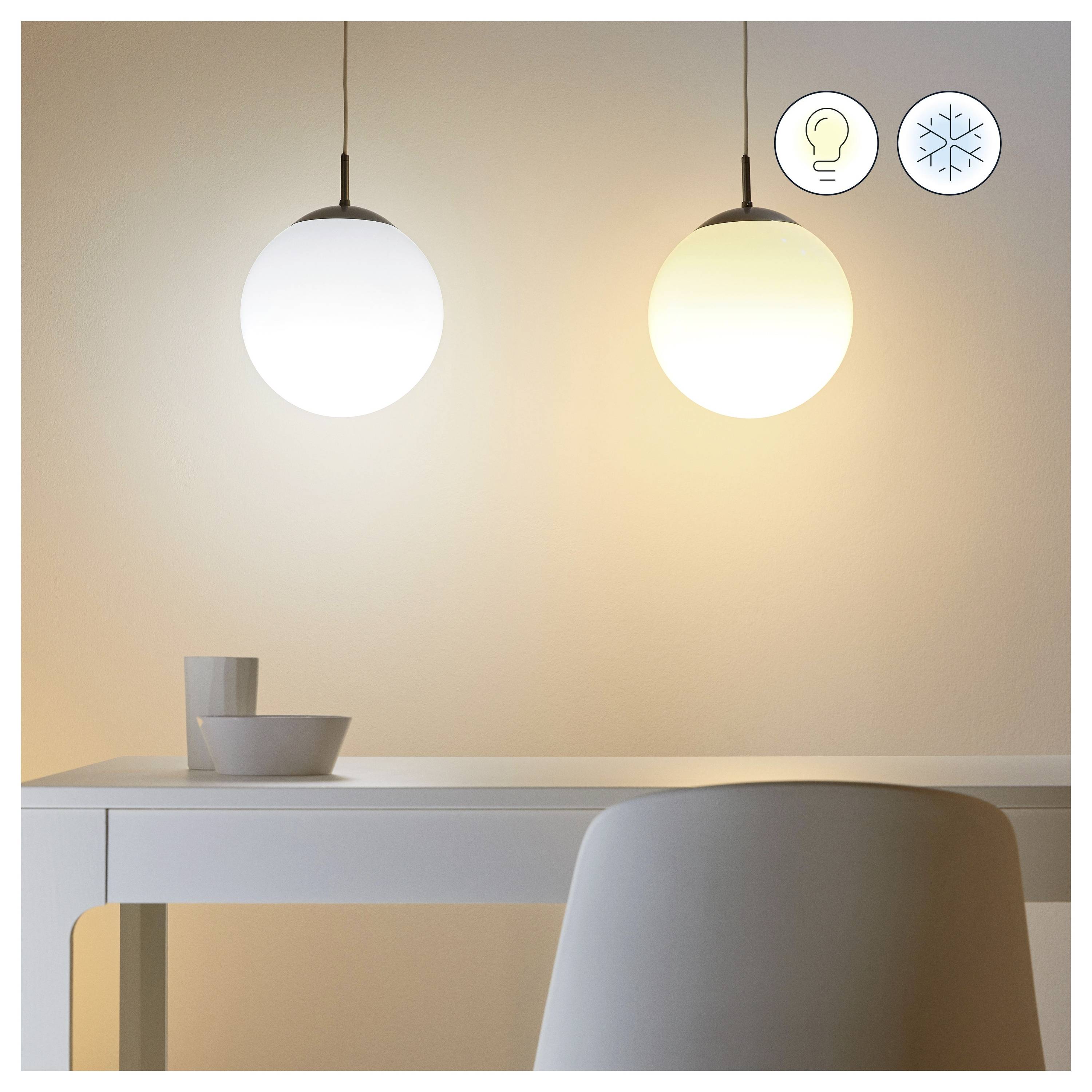 Ein Raum mit zwei Pendelleuchten über einem weißen Tisch. Die linke Leuchte ist kühl-weiß; die rechte ist warmweiß. Symbole zeigen Glühbirne und Schneeflocke.