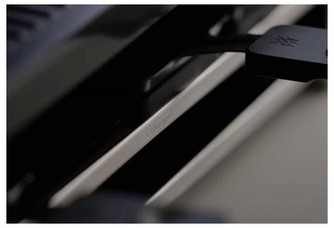 'Eine Nahaufnahme eines schwarzen USB-Connectors, der in ein dunkles Gerät eingesteckt ist, wobei das Gerät im Hintergrund teilweise sichtbar ist und so die Konnektivität hervorhebt.'