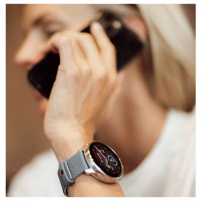 Person, der telefoniert und eine Smartwatch trägt, die Gesundheitsdaten wie Schritte und Herzfrequenz anzeigt.
