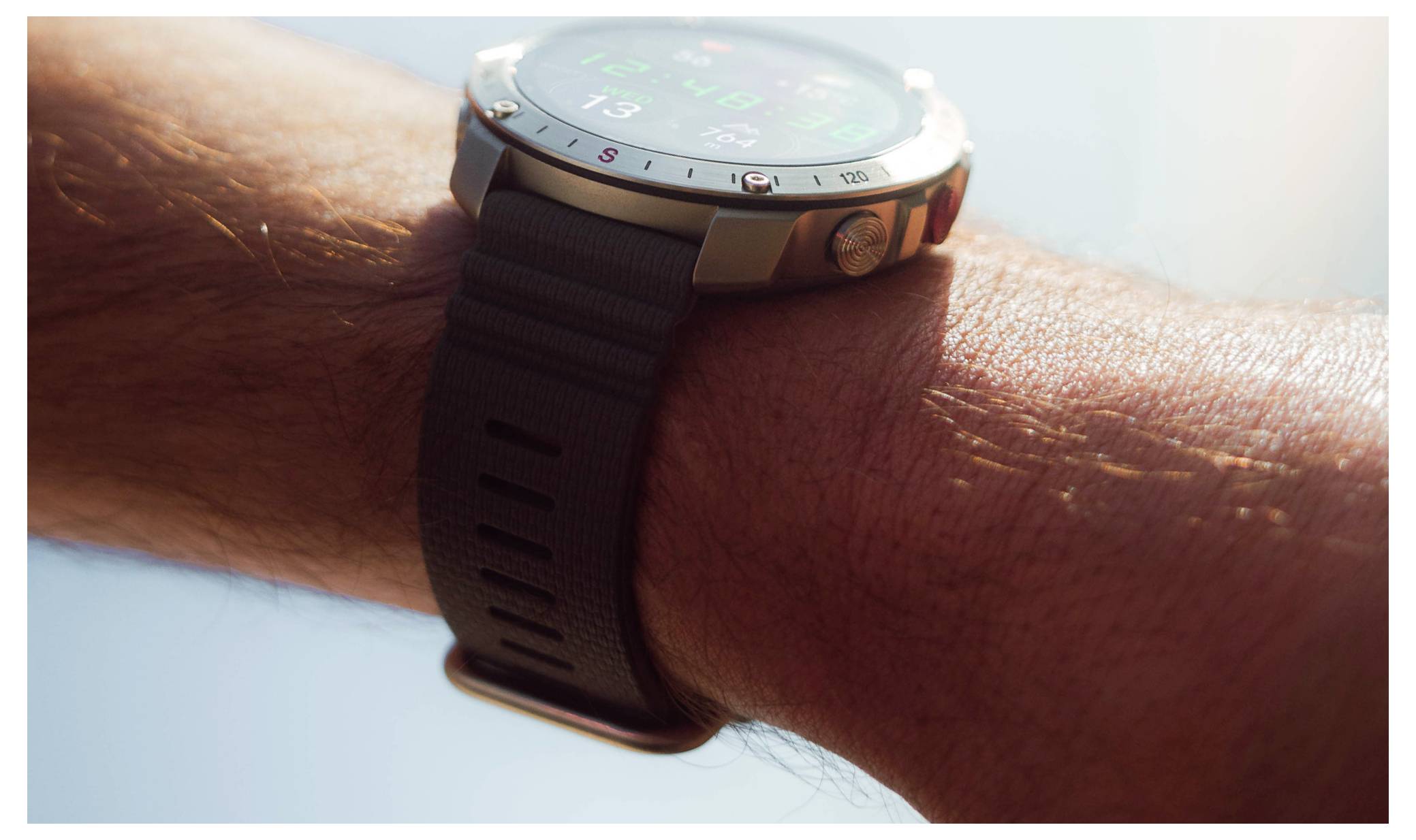 Eine Nahaufnahme einer digitalen Armbanduhr am Handgelenk einer Person, die verschiedene Gesundheitsmetriken auf ihrem Bildschirm bei hellem Tageslicht anzeigt.