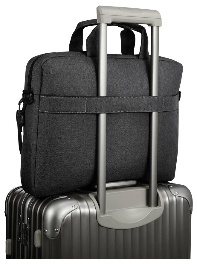 Eine schwarze Stofftasche mit Trageriemen ist sicher am Griff eines silbernen Hartschalenkoffers befestigt und zeigt damit praktische Reisefunktionalität.