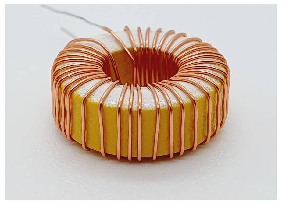 Eine Toroidspule mit Kupferdraht, die um einen gelben Kern gewickelt ist. Die Anschlüsse ragen aus der Spule und werden in der Elektronik zur Induktivitätserzeugung verwendet.