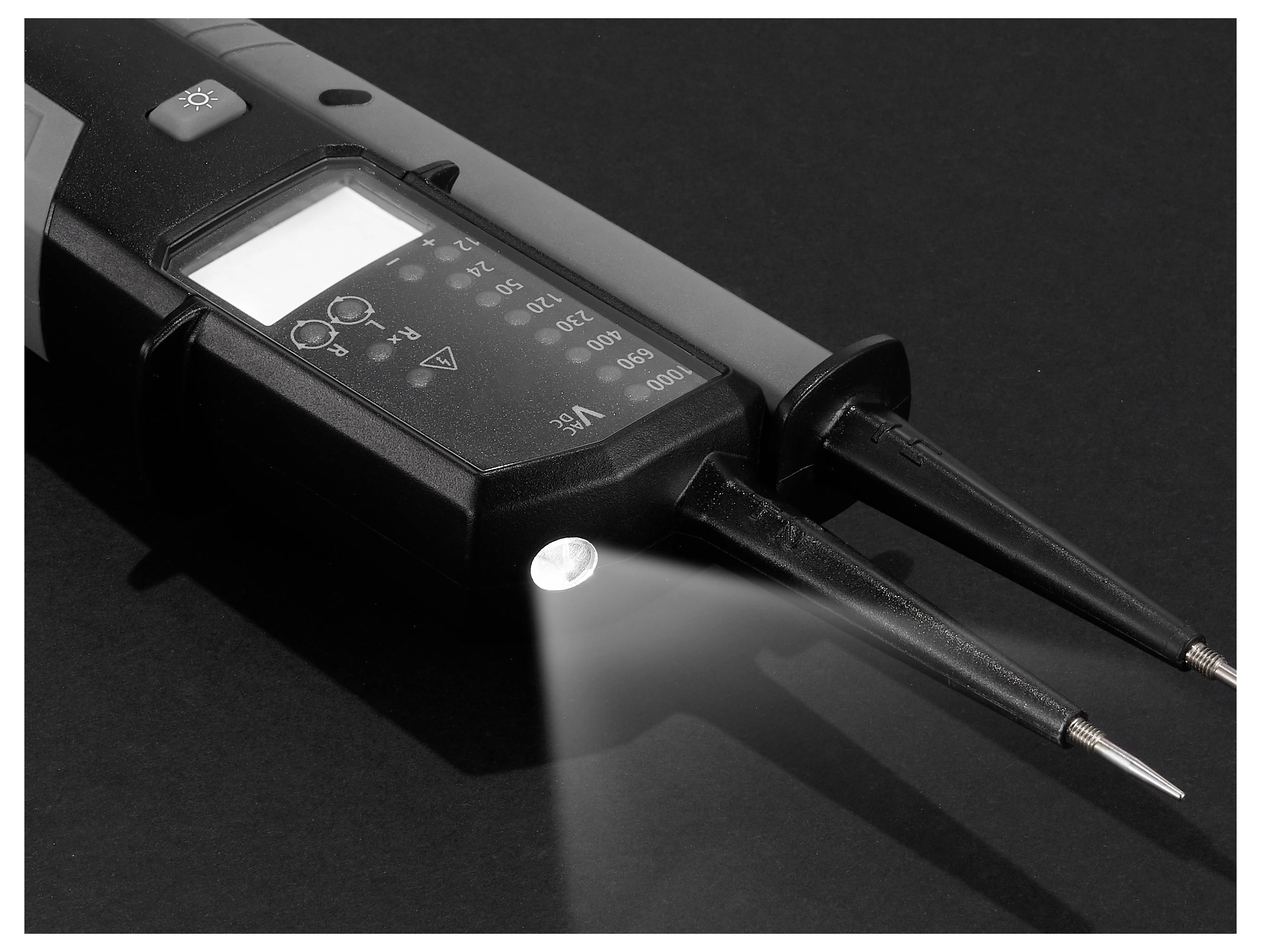 Digitales Spannungsprüfgerät mit zwei Prüfspitzen und beleuchtetem Display, dargestellt auf einer dunklen Oberfläche mit nach vorne leuchtender Taschenlampe.