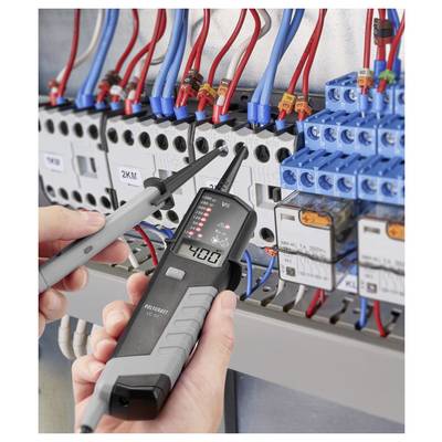 Techniker testet ein elektrisches Schaltschrank mit einer Spannungsprüfer-Sonde, umgeben von roten und blauen Drähten und Schaltkomponenten.
