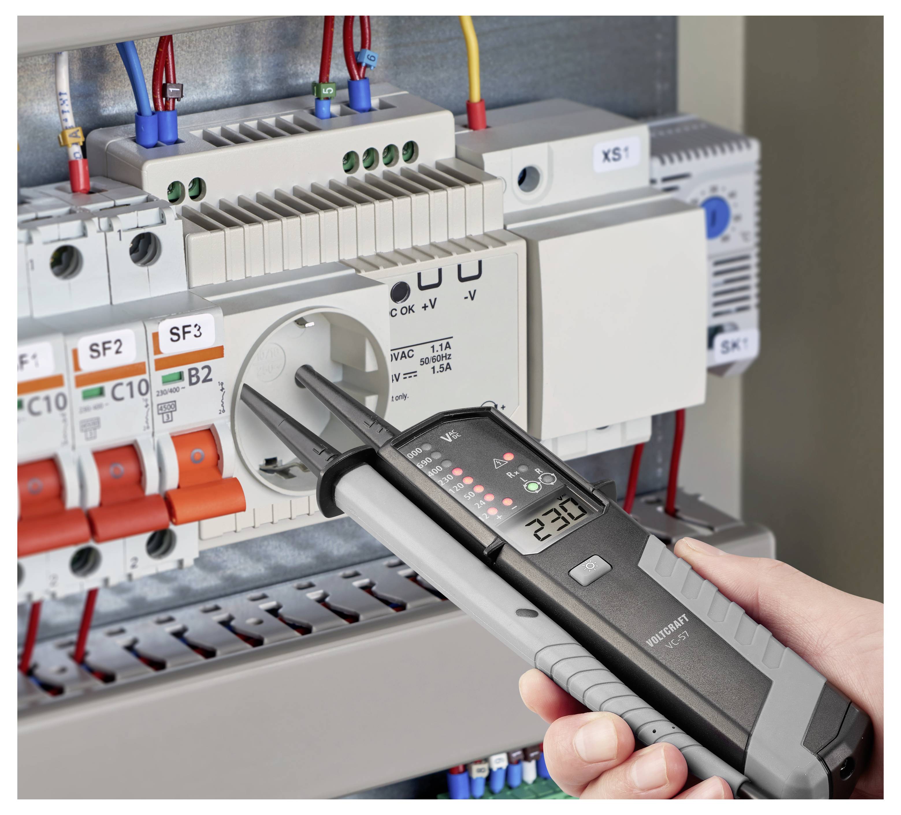 Tragbares Elektroprüfgerät, das ein Stromlaufplan misst, wobei Messspitzen in eine Steckdose neben Leistungsschaltern und Verdrahtung eingeführt werden.