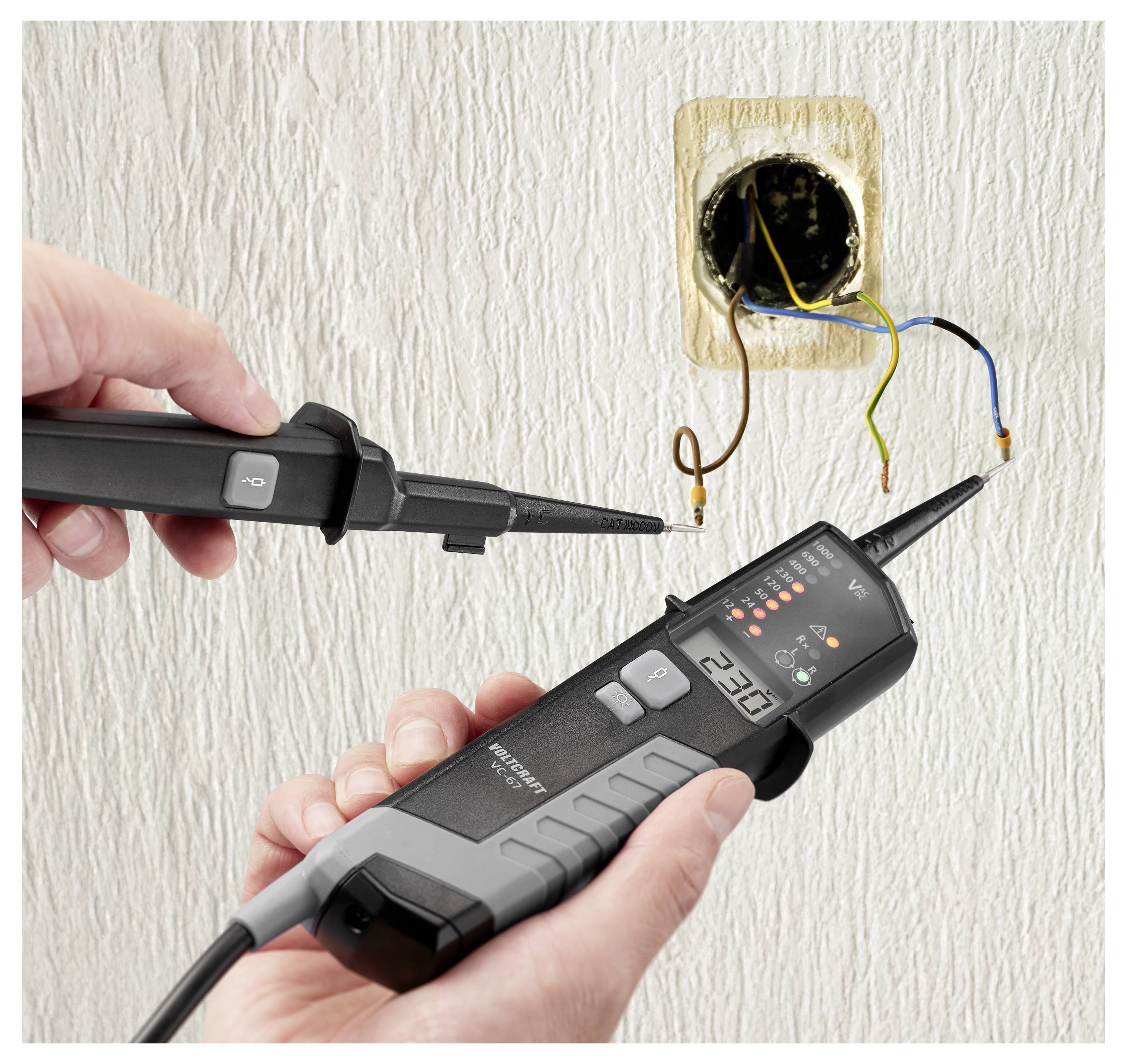 Techniker testet freigelegte Wandverkabelung mit einem Spannungsprüfer und einer Messsonde in der Nähe einer offenen Elektroverteilerdose.