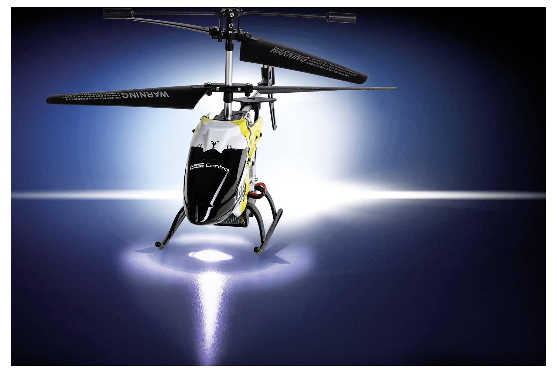 Ein ferngesteuerter Hubschrauber schwebt über einer beleuchteten Oberfläche und wirft einen Scheinwerferkegel.