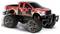 Ein rot-schwarzer ferngesteuerter Geländewagen mit überdimensionalen Reifen, der einem Ford F-150 Modell nachempfunden ist, in Bewegung dargestellt.