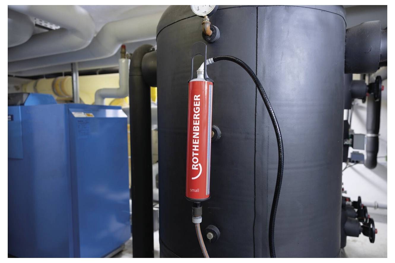 Ein Rothenberger-Werkzeug, angebracht an einem großen industriellen Tank, verwendet in der Sanitär- oder HVAC-Umgebung, mit umgebender Maschinerie und Rohrleitungen im Sichtfeld.