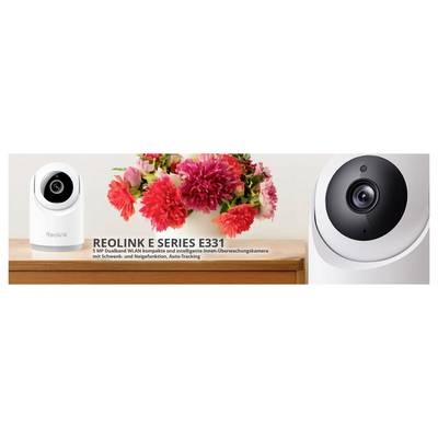 'Reolink E Series E331' Überwachungskamera, weiß mit schwarzer Linse, neben rosa und roten Blumen, auf einem Holzregal. Text beschreibt Funktionen.