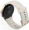 Eine beige Smartwatch mit einem matten Armband und goldenen Akzenten wird präsentiert, wobei die Rückseite mit Sensoren und mehreren Armbandhalterlöchern für eine verstellbare Passform zu sehen ist.