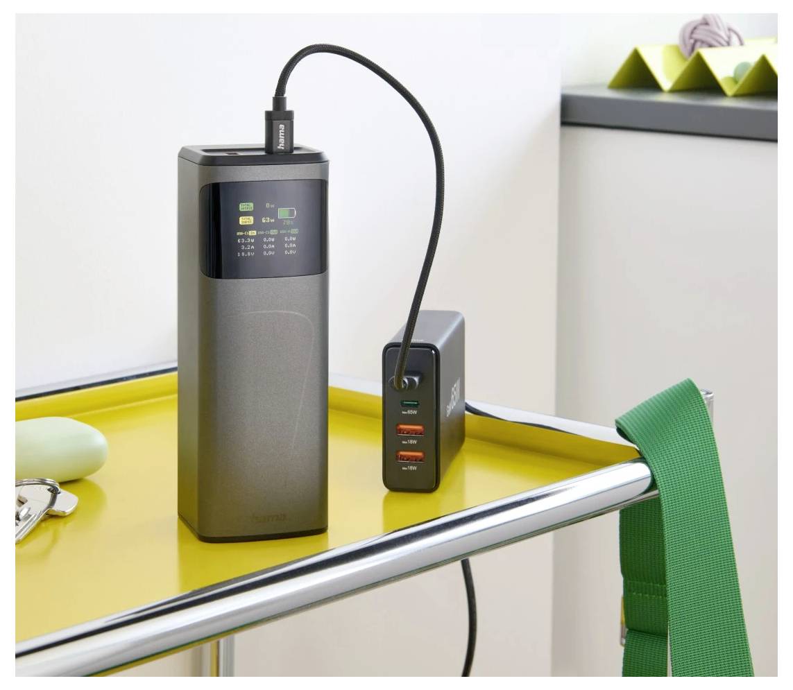 Ein Powerbank und ein Multiport-Ladegerät auf einem gelben Tablett, mit einem grünen Riemen, der seitlich sichtbar ist und einen energieeffizienten Technologie-Aufbau zeigt.