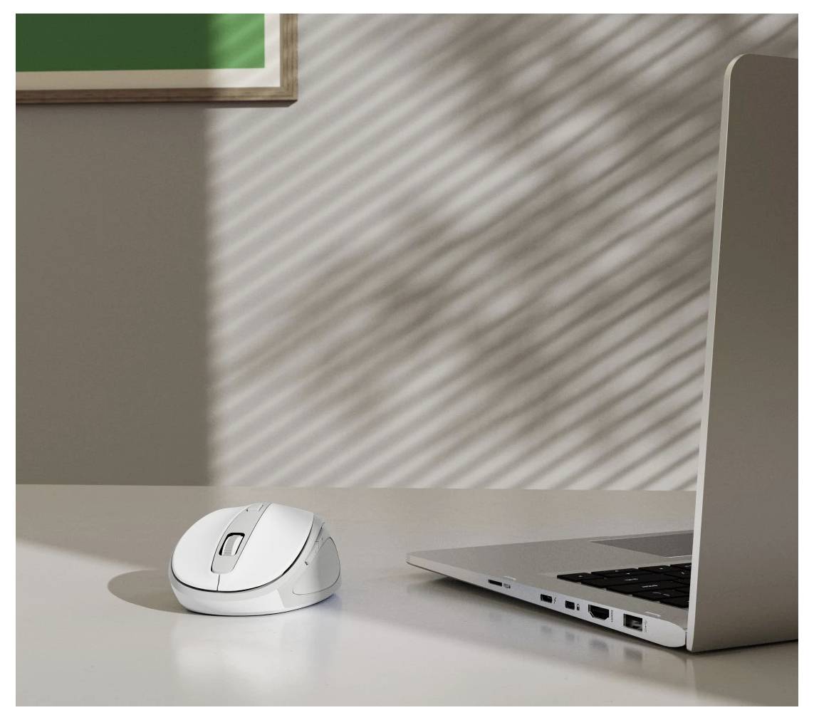 Eine weiße Computermaus und ein Laptop auf einem weißen Schreibtisch, über den die Schatten von Jalousien geworfen werden und ein gestreiftes Muster erzeugen.