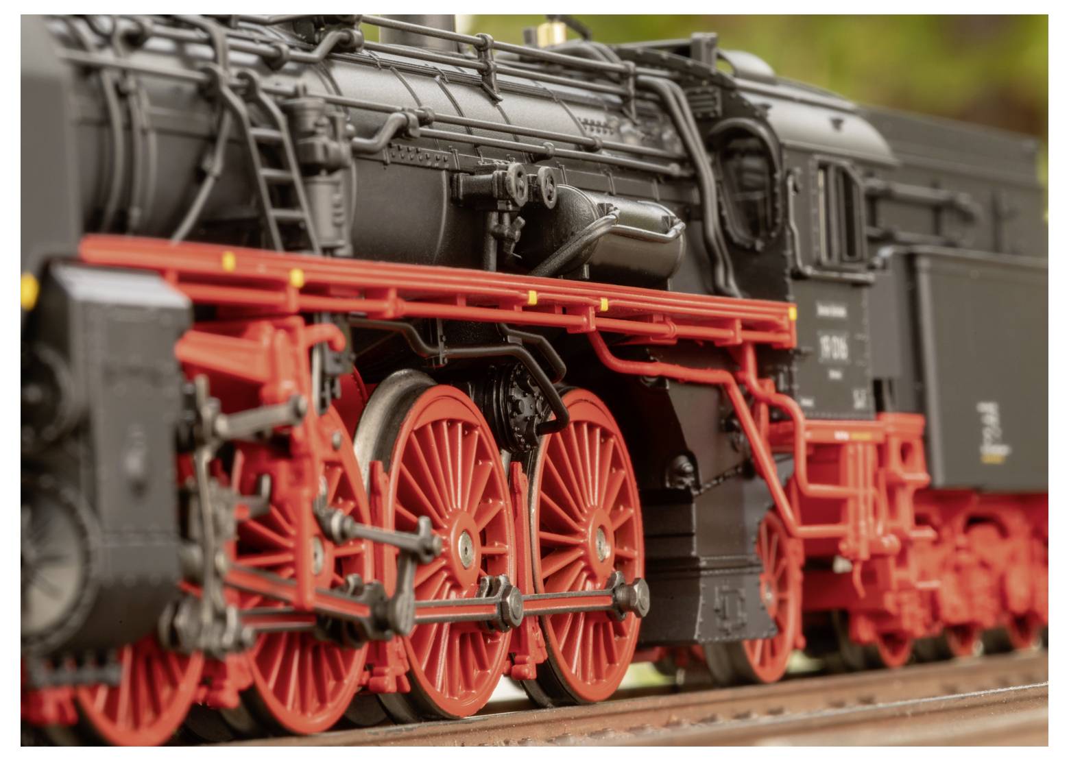 Eine detaillierte Nahaufnahme einer schwarz-roten Dampflokomotive im Vintage-Stil, die komplexe Räder und mechanische Komponenten in all ihren Details zeigt.