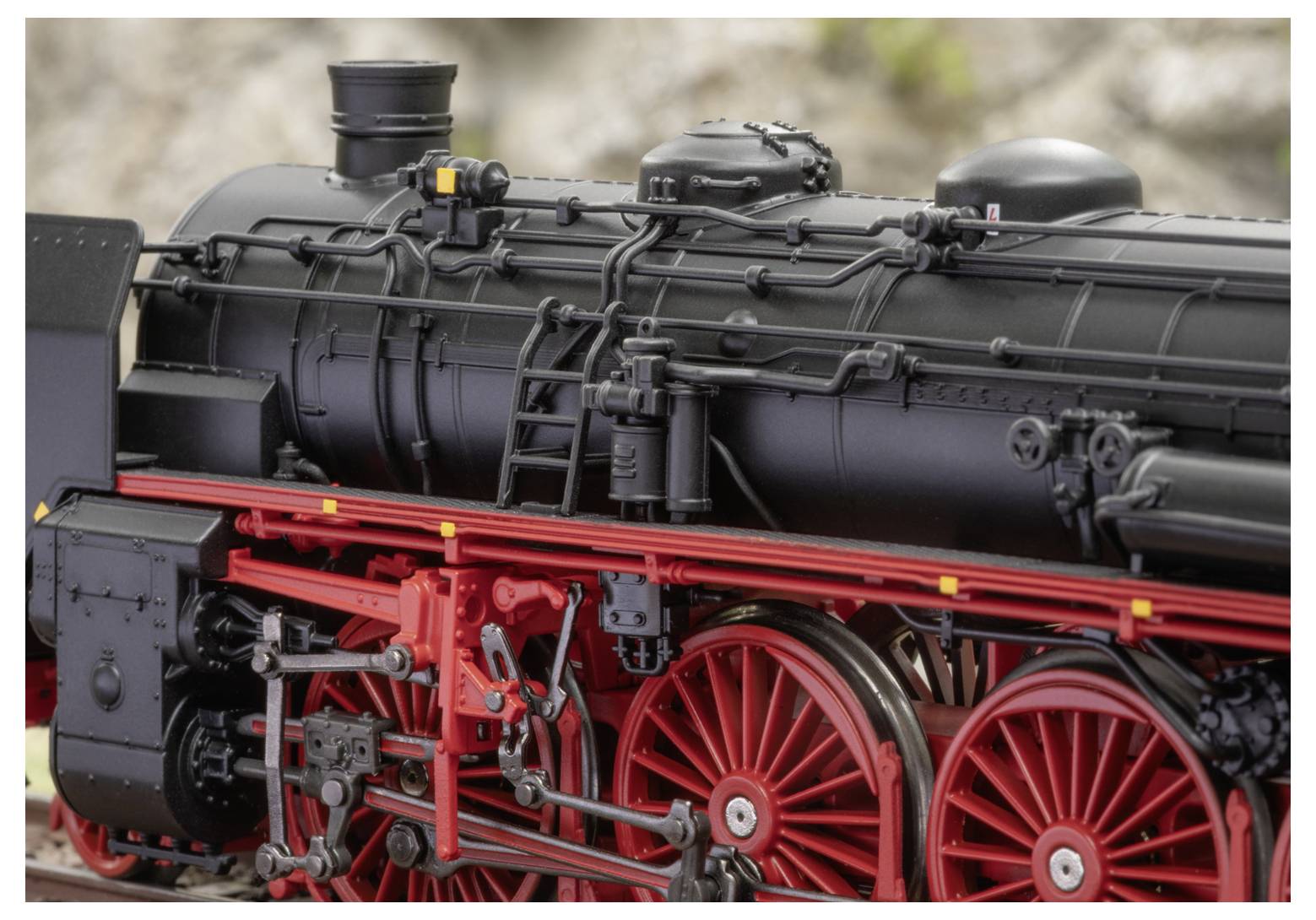 Ein Nahaufnahmebild einer traditionellen schwarzen Dampflokomotive mit leuchtend roten Rädern und komplexen mechanischen Details.