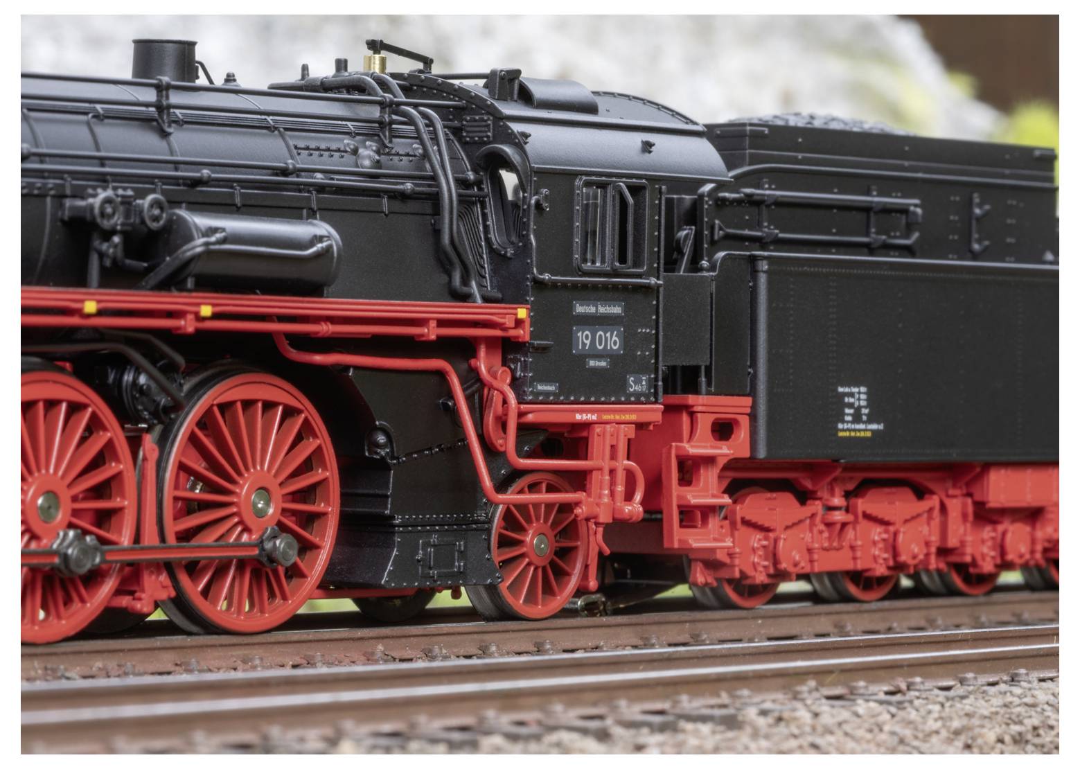 Eine Dampflokomotive im Modell mit schwarzem Gehäuse und roten Rädern, die mit kunstvollen Details ihrer Maschine und Räder ausgestellt ist.