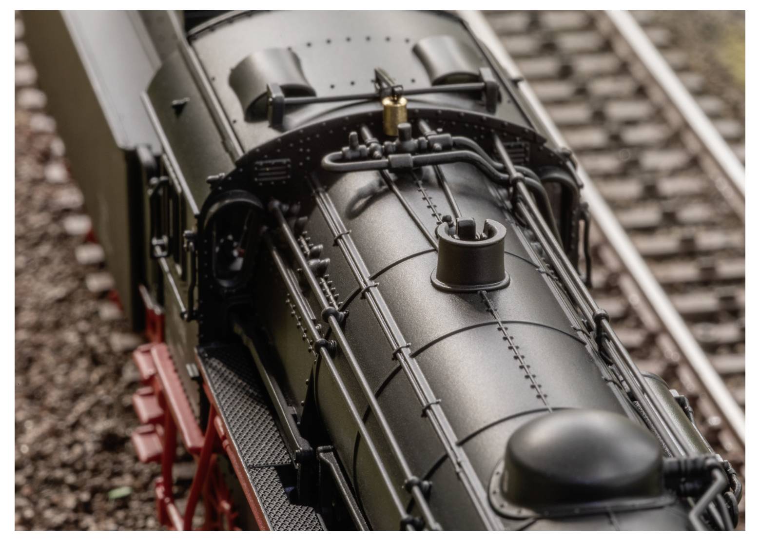 Modell-Dampflokomotive auf Eisenbahnschienen mit detaillierter Ansicht der Lokomotive und metallischer Komponenten, die kunstvolle Handwerkskunst zur Schau stellt.