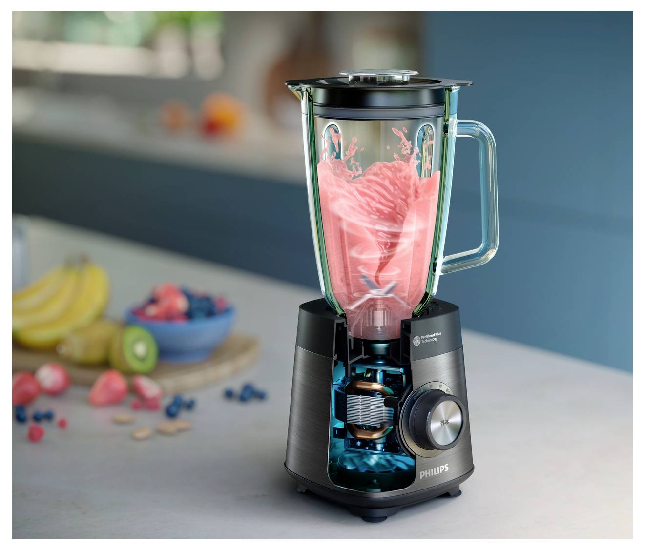 Ein schwarzer Mixer auf einer Küchenarbeitsplatte, der eine hellrosa Flüssigkeit püriert. Umgebende Gegenstände sind verstreute Erdbeeren, Bananen und eine Schüssel mit Beeren.