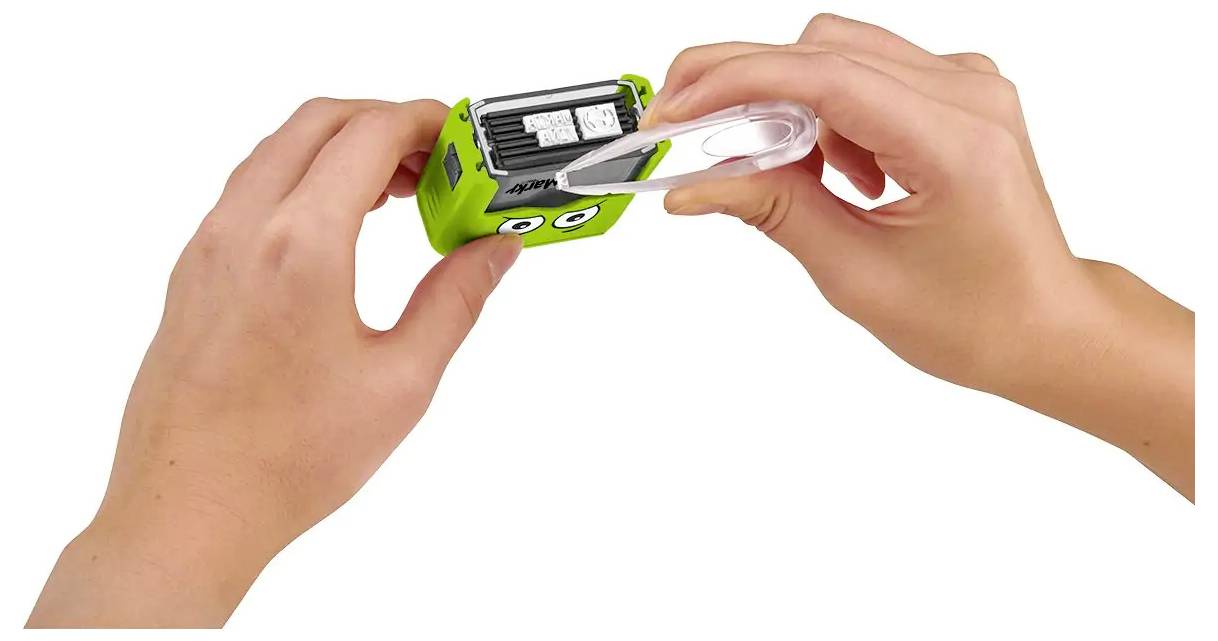 Hände, die einen grünen Anspitzer mit einem durchsichtigen Deckel halten, wobei der Deckel entfernt wird und zwei Anspitzeröffnungen sichtbar werden, die mit Bleistiftgrößen gekennzeichnet sind.