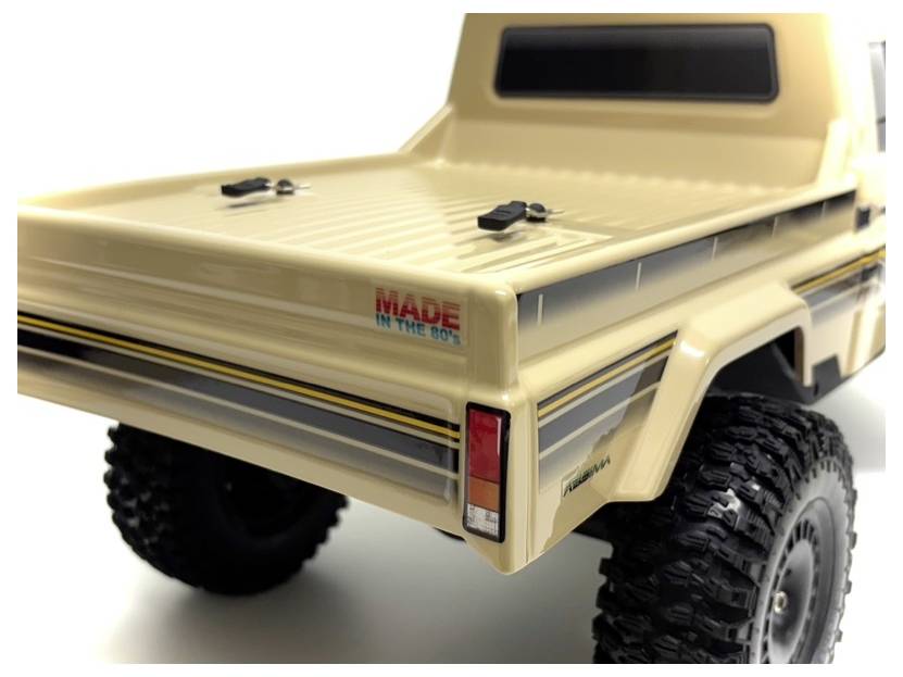 Ein beiger Spielzeug-Lastwagen mit großen Reifen und einem gestreiften Design. Die Worte ‚Made in the 80's' sind auf dem hinteren Panel gedruckt.