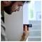 Eine Person verwendet ein digitales Messgerät an einer Wand und richtet es auf eine Treppe, wobei sie eine Messung durchführt.
