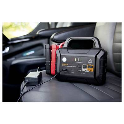 Ein tragbares Autobatterieladegerät mit Starthilfekabeln liegt auf einem Autositz, einsatzbereit.