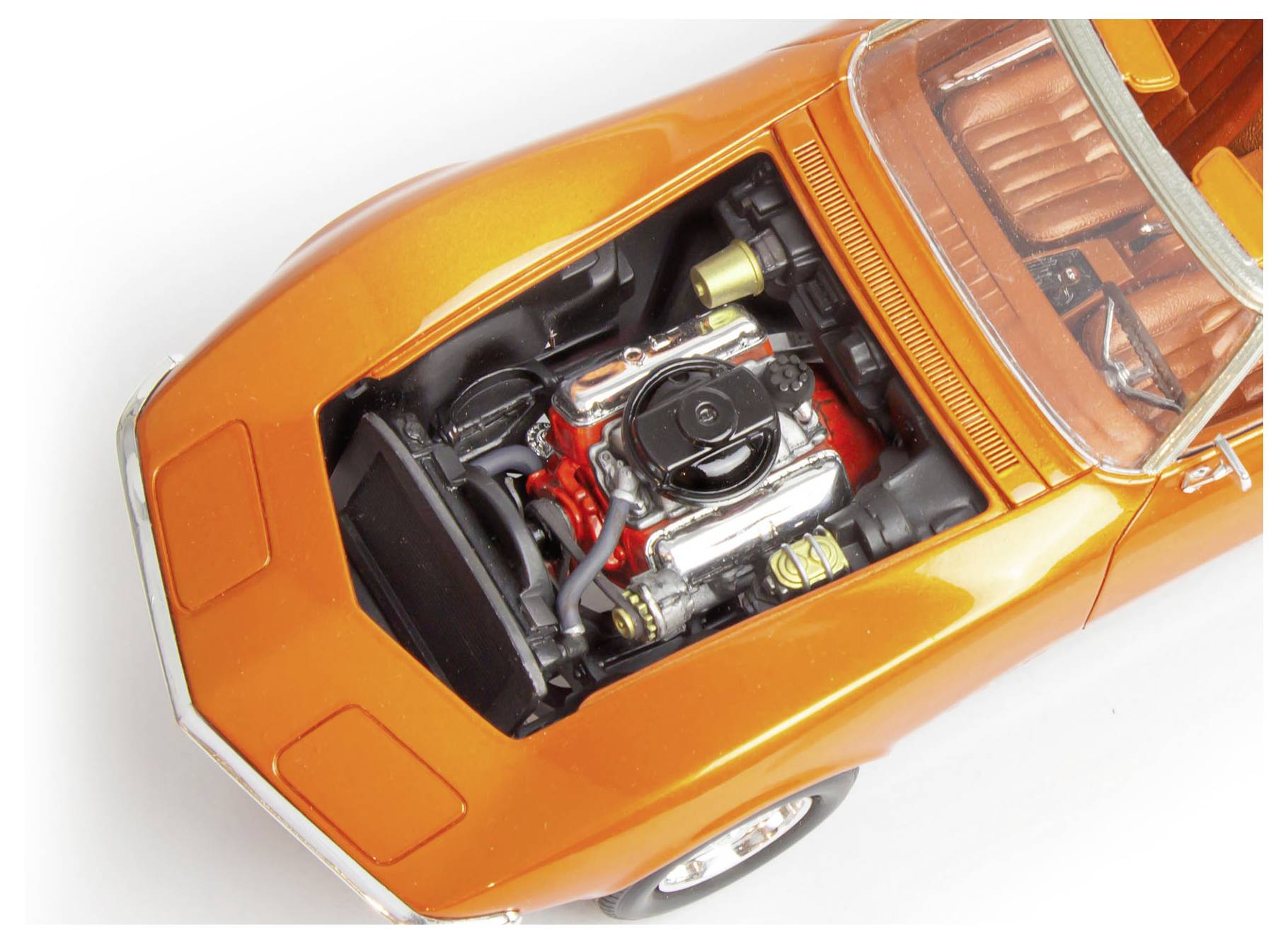 Ein orangefarbenes klassisches Automodell mit geöffneter Motorhaube, die einen detaillierten Motor freilegt. Das Interieur ist sichtbar und zeigt einen Teil der Sitzgelegenheiten.