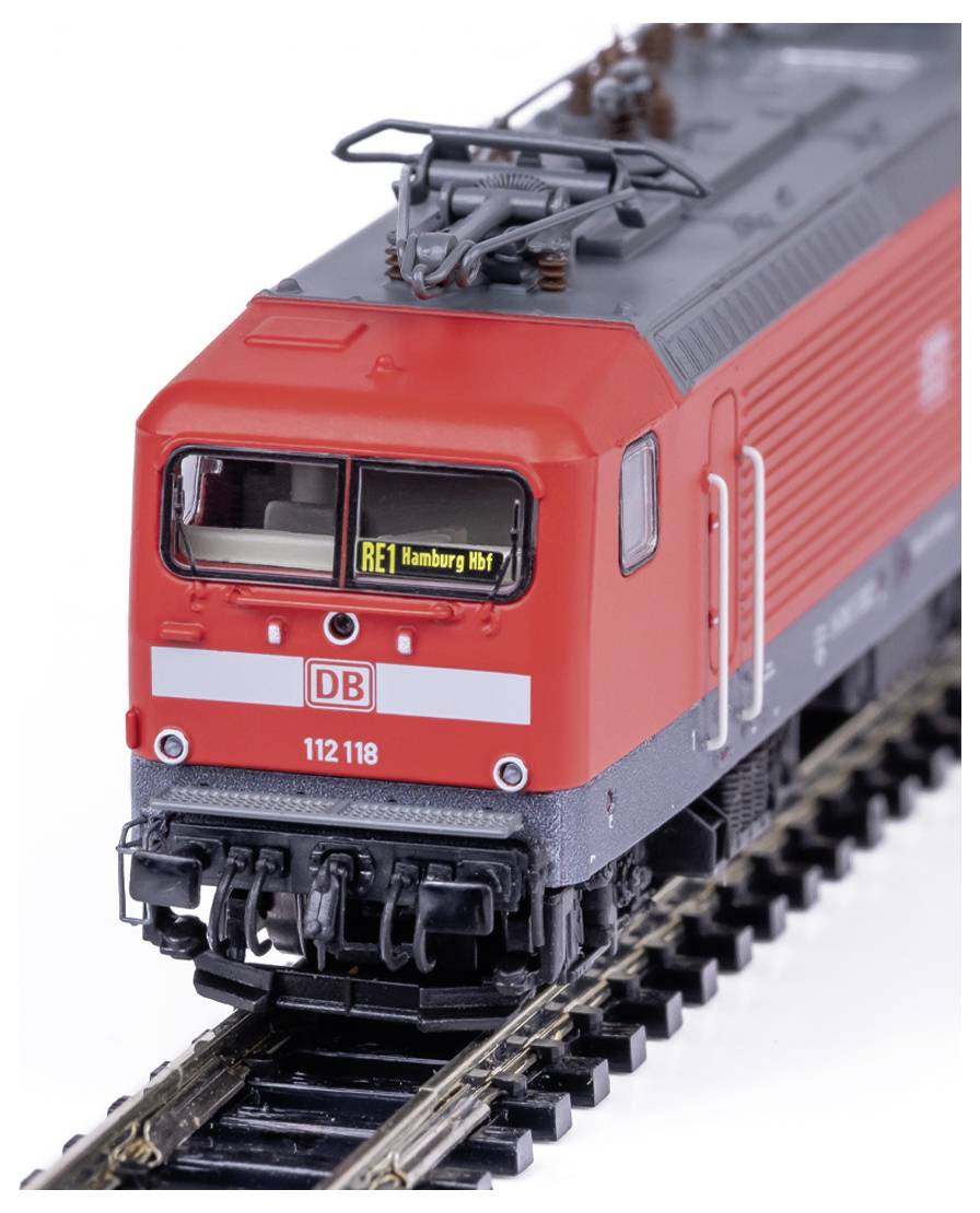 Ein Modell einer roten Zuglokomotive auf Schienen, mit der Beschriftung "RE1 Hamburg Hbf" auf der Frontanzeige.