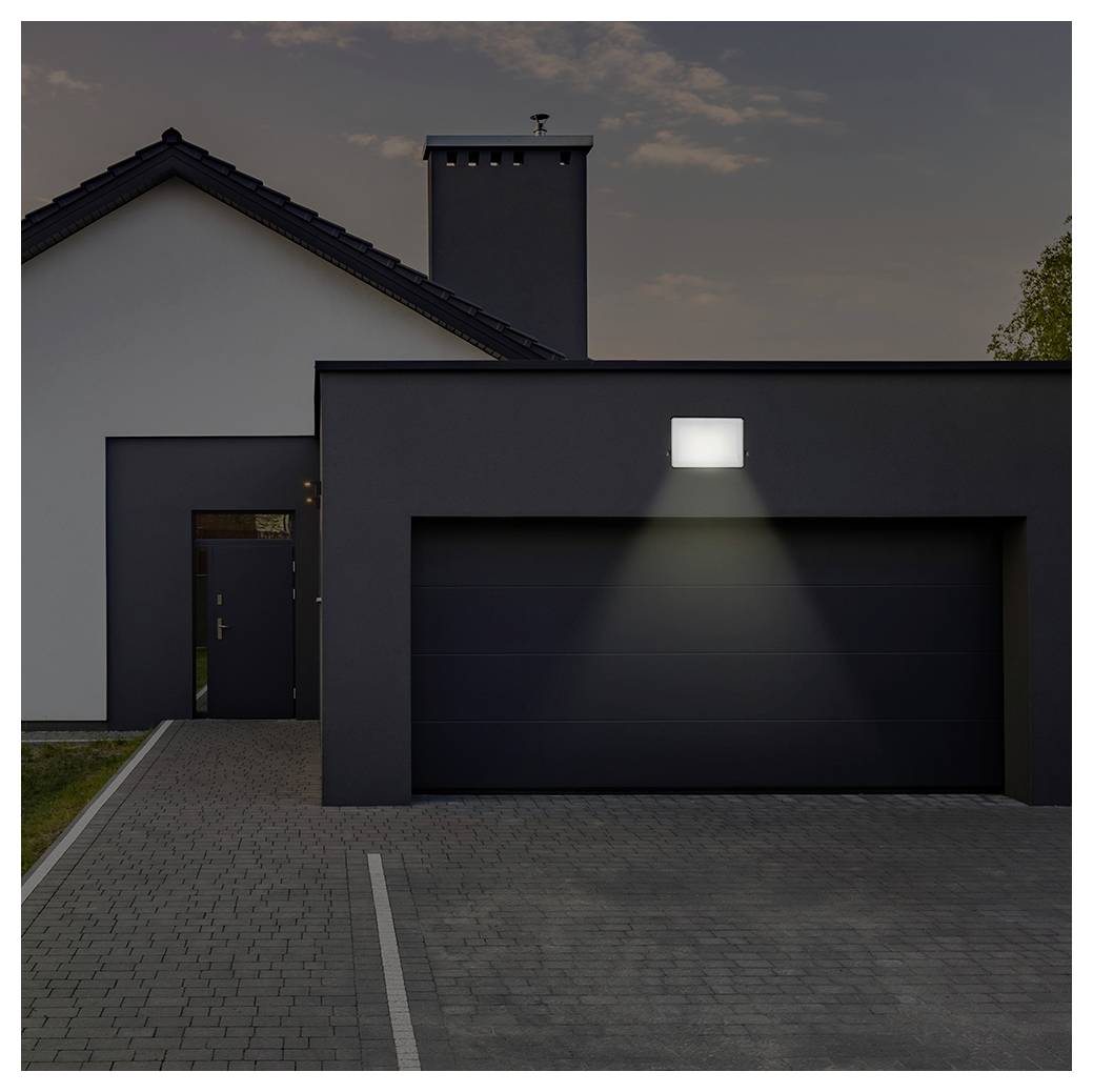 Ein modernes Haus in der Abenddämmerung mit einer einzigen Außenleuchte, die die Auffahrt und den Garageneingang beleuchtet.