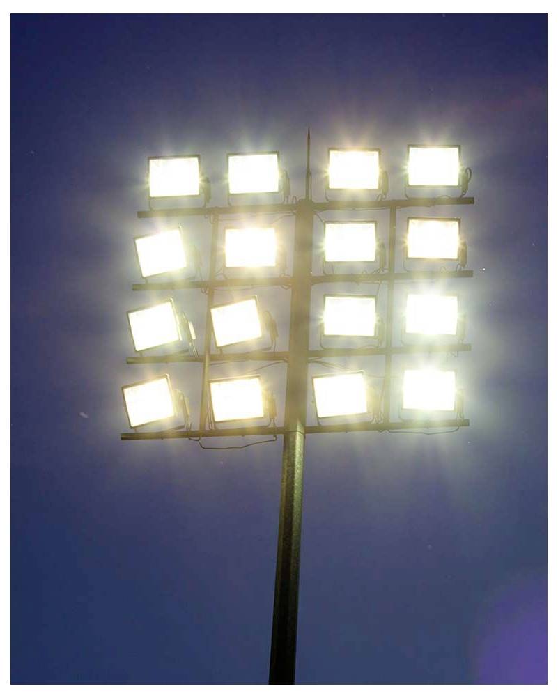 Sechzehn helle Stadionscheinwerfer auf einem hohen Mast erleuchten den Nachthimmel.