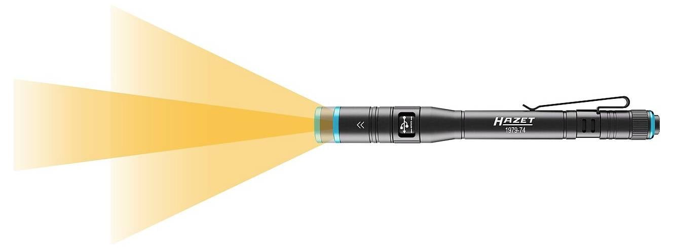 Eine schmale, schwarze Hazet-Taschenlampe strahlt einen breiten Kegel von gelbem Licht von vorne aus, mit einer Taschenklemme, die nahe dem hinteren Ende befestigt ist.