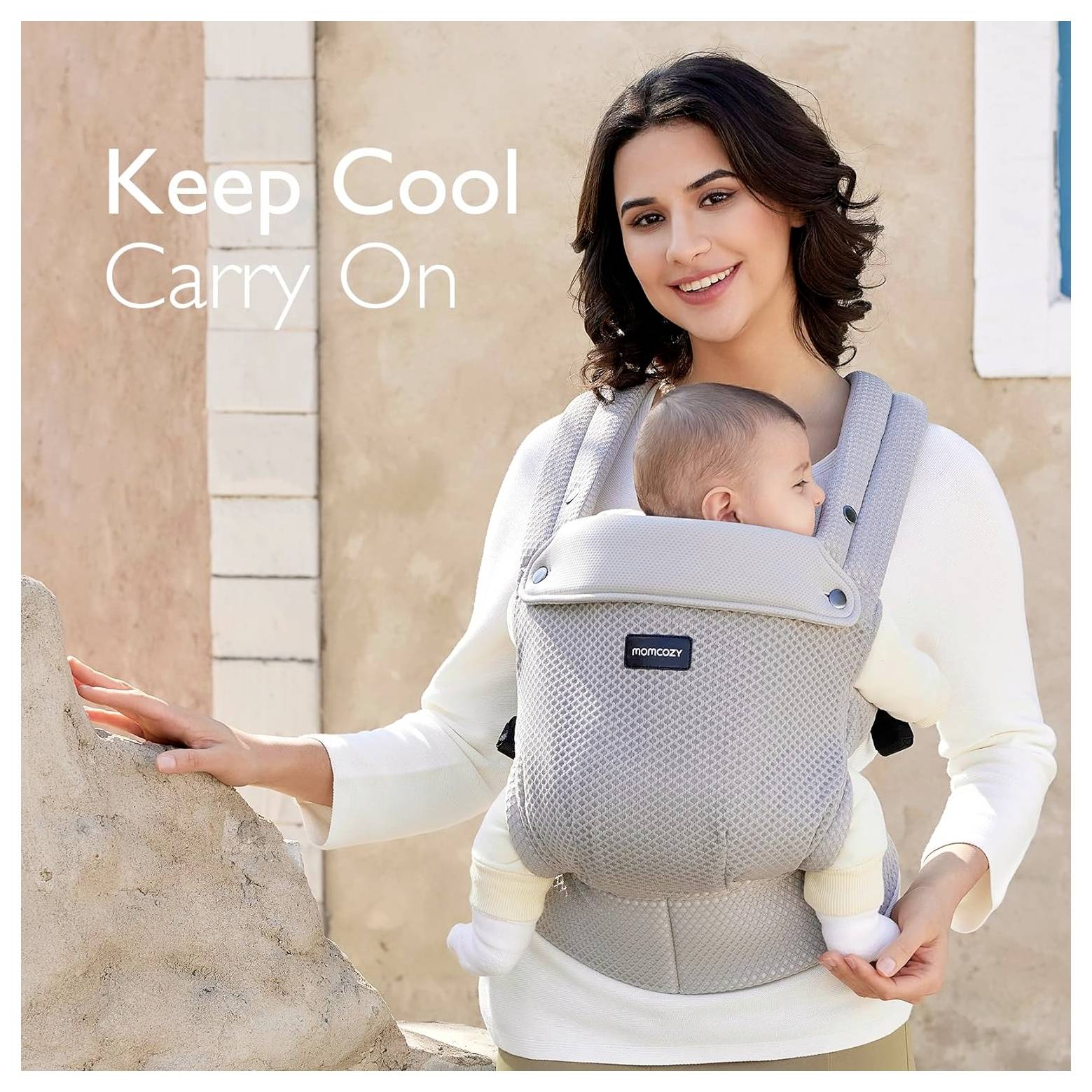 Eine Frau, die ein Baby in einem Tragegurt trägt, lächelt, während sie nahe einer beigen Wand steht. Text auf dem Bild liest sich: Cool bleiben, weiter geht's.