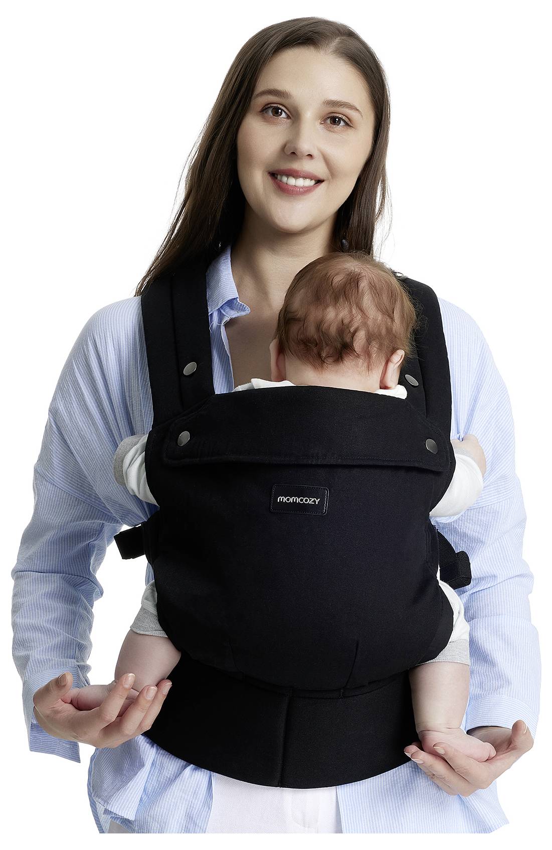 Eine Frau lächelt in die Kamera, während sie ein Baby in einem schwarzen Babytrage trägt. Das Baby ist zur Frau gerichtet.