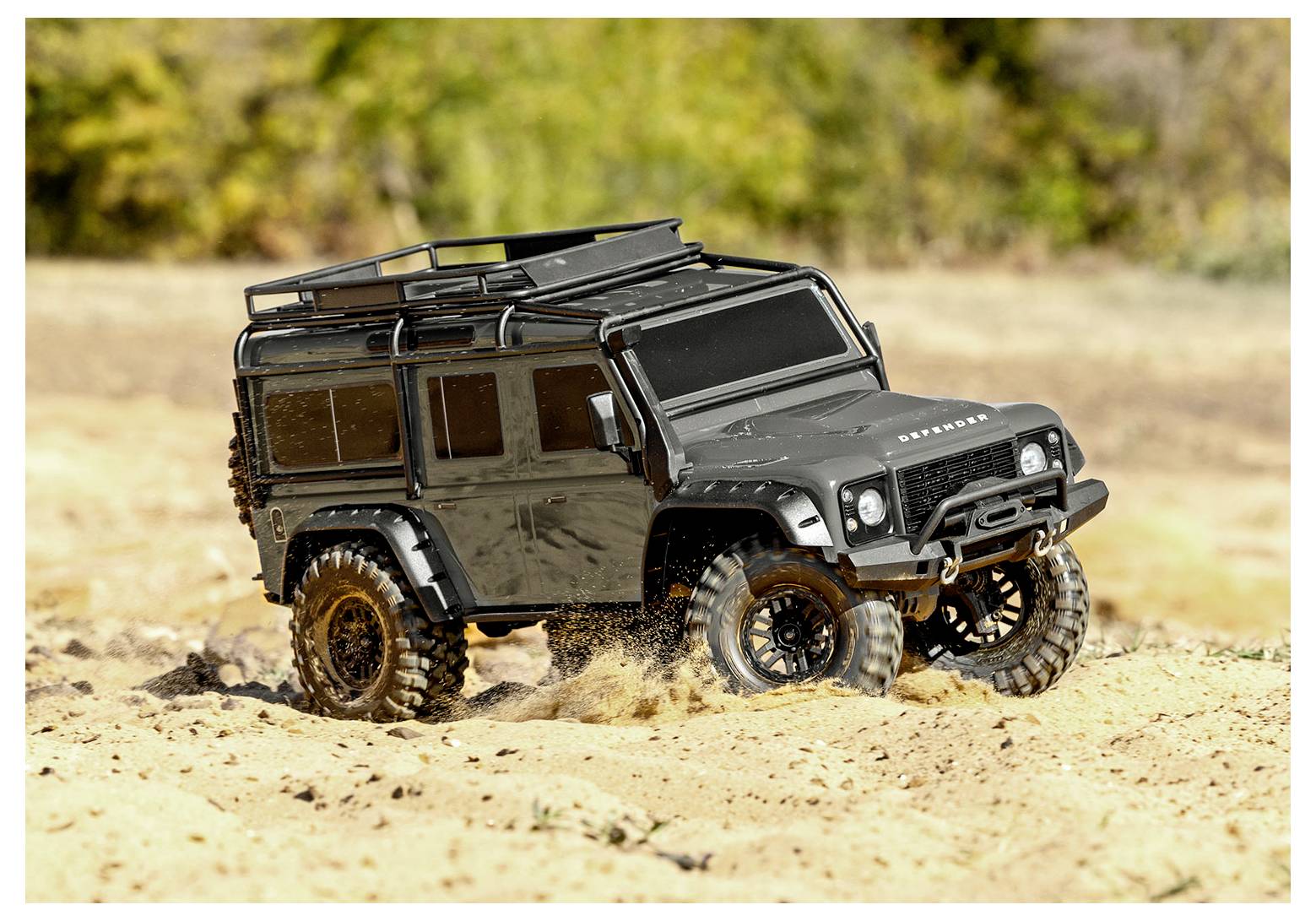 Ein schwarzes Geländefahrzeug fährt über sandiges Terrain und zeigt dabei seine robusten Reifen und das robuste Design zum Durchqueren schwieriger Landschaften.