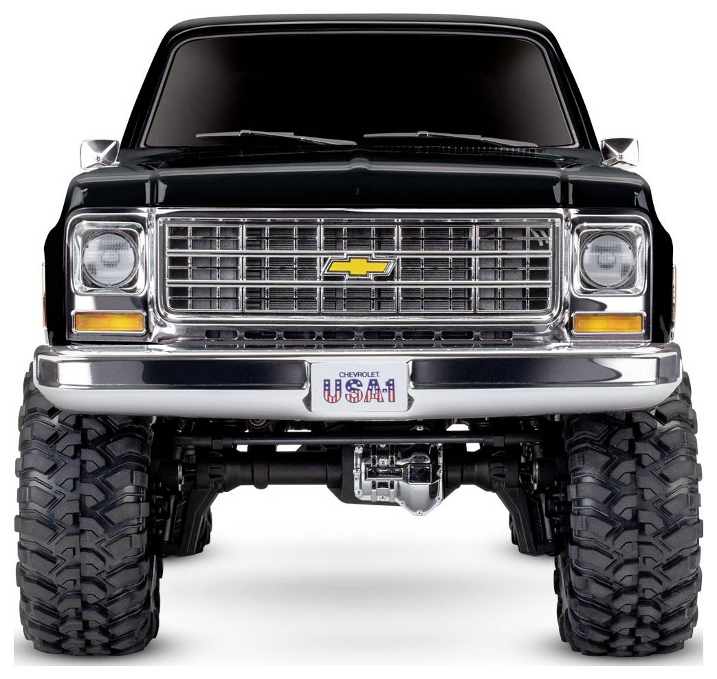 Frontansicht eines dunkelgrünen Lastwagens mit großen, robusten Reifen und einem markanten Chrom-Kühlergrill, auf dem ein Nummernschild mit der Aufschrift ‚Chevrolet USA1' angebracht ist.