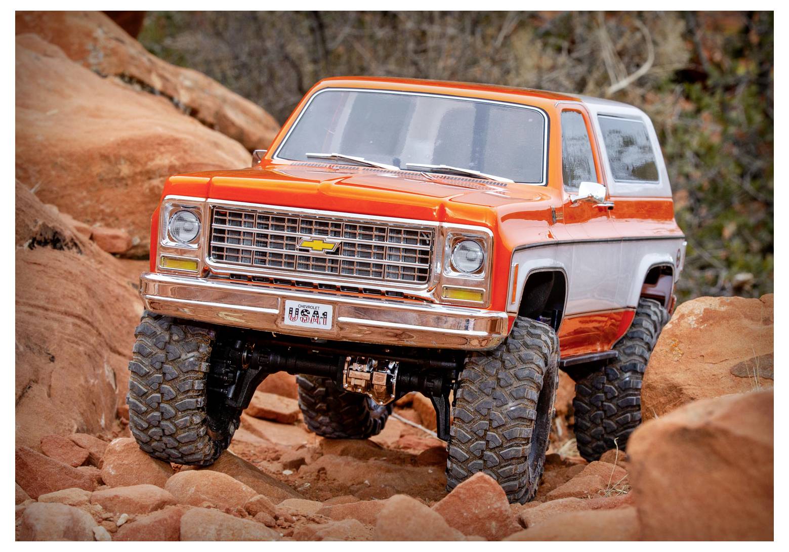 Ein heller orange-weißer Vintage-SUV mit großen Geländereifen bewegt sich über felsiges Gelände und demonstriert seine robusten Fähigkeiten.