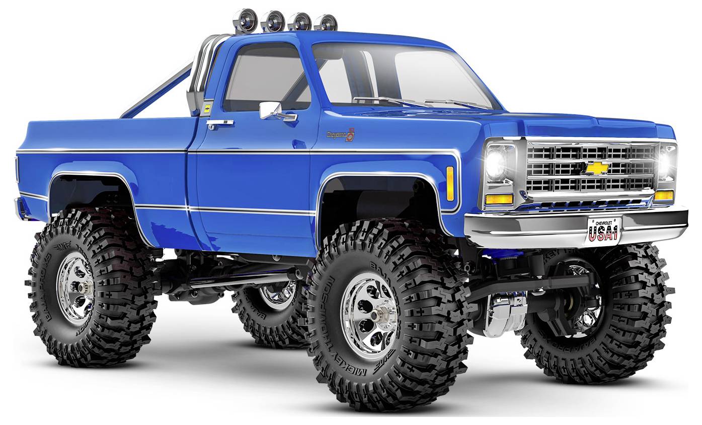 Blauer Chevrolet-Truck mit Höherlegung, Geländereifen und Chromdetails, der vor einem weißen Hintergrund geparkt ist.