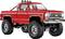 Ein knallroter restaurierter Vintage-Pickup-Truck mit großen Geländereifen, Chromdetails und einer Überrollbügel, vor einem einfarbigen weißen Hintergrund.