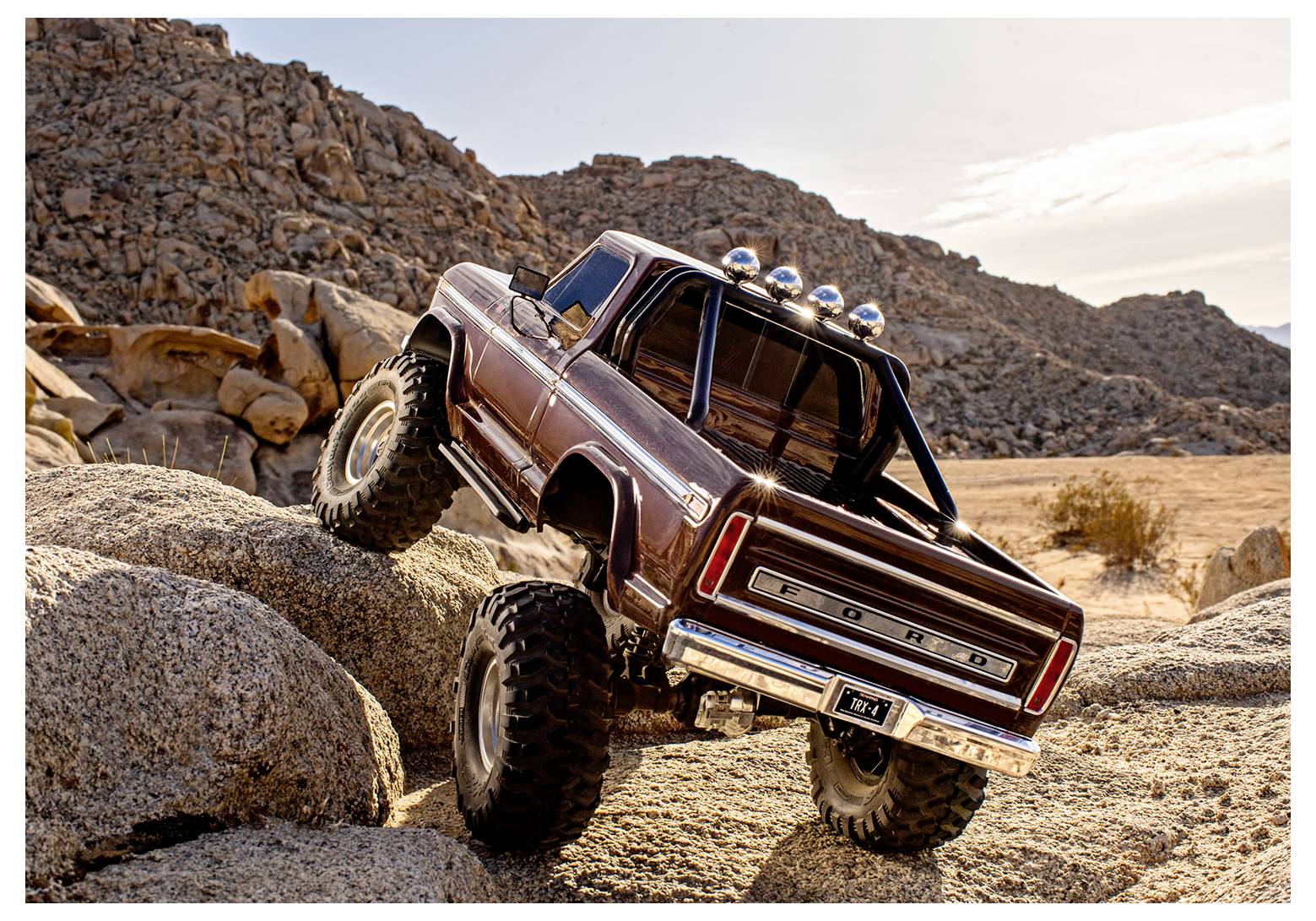 Ein ferngesteuerter Truck erklimmt felsiges Gelände in einer Wüstenlandschaft und demonstriert seine Geländegängigkeit unter einem strahlend klaren Himmel.