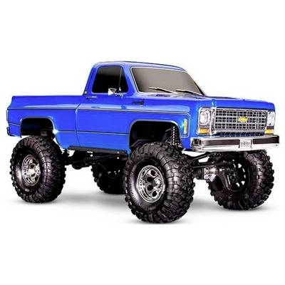 Ein hell blauer, angehobener Vintage-Pickup-Truck mit großen Offroad-Reifen und Chrom-Akzenten, der auf einem weißen Hintergrund geparkt ist.
