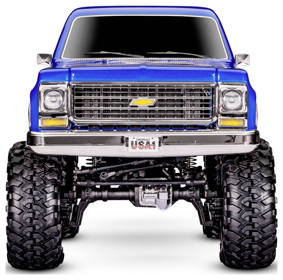 Blauer Pickup-Truck mit großen Reifen und einem Nummernschild mit der Aufschrift "USA1", von vorne betrachtet, mit Blick auf seinen Chrom-Kühlergrill und die Fahrwerkskomponenten.