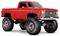 Ein angehobener roter Pickup-Truck mit großen Reifen und Chrom-Akzenten ist zu sehen, der ein Off-Road-Aussehen vermittelt und vor einem weißen Hintergrund geparkt ist.