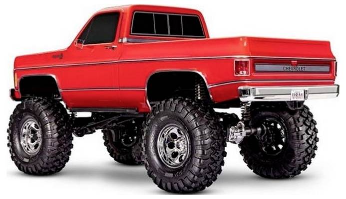 Ein roter Pickup-Truck mit übergroßen Reifen auf einem isolierten weißen Hintergrund. Der Truck verfügt über ein Vintage-Design mit Chrom-Akzenten.