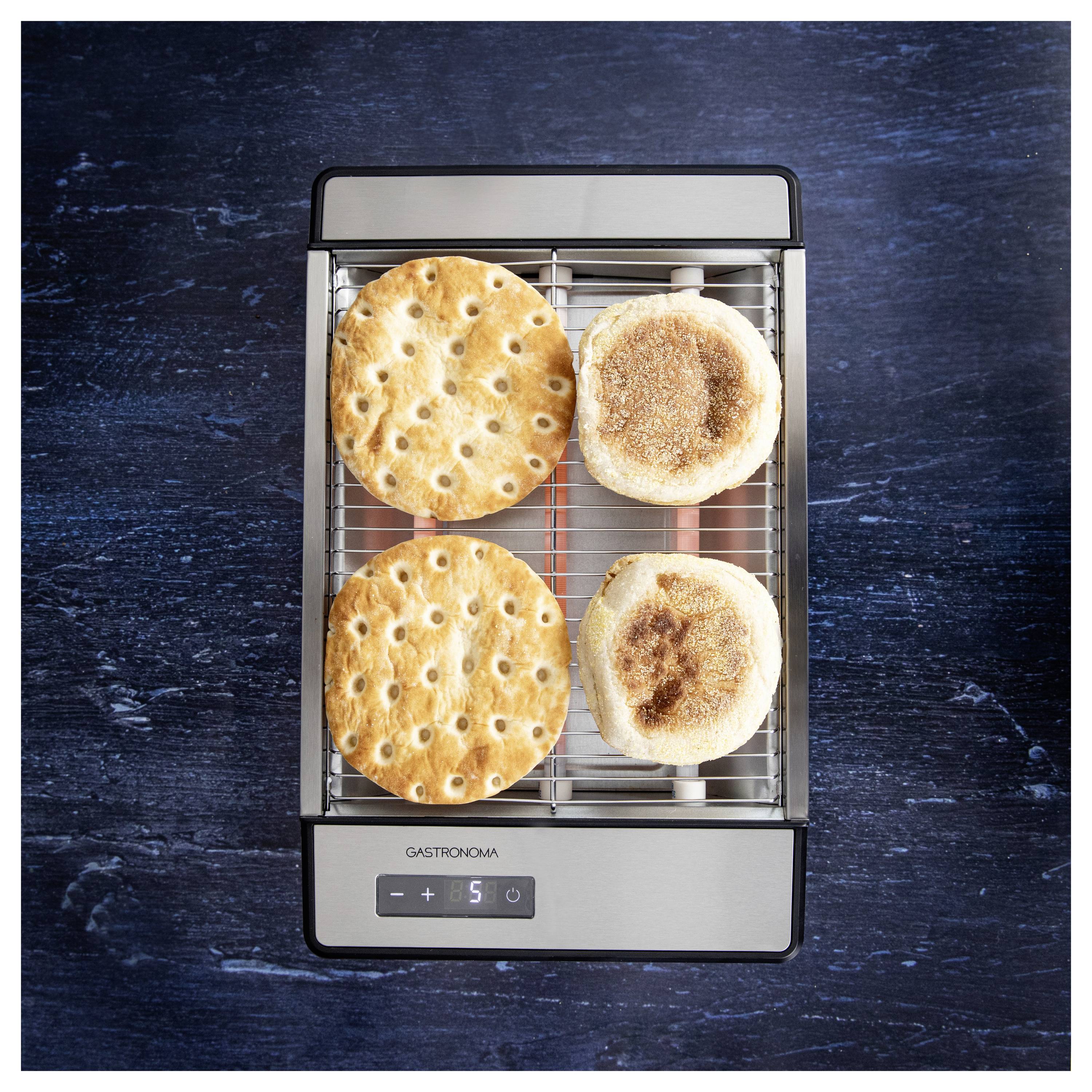 Ein 'Gastronoma' Toaster mit zwei umkreisten Brotscheiben und zwei englischen Muffins auf einer blauen Oberfläche.