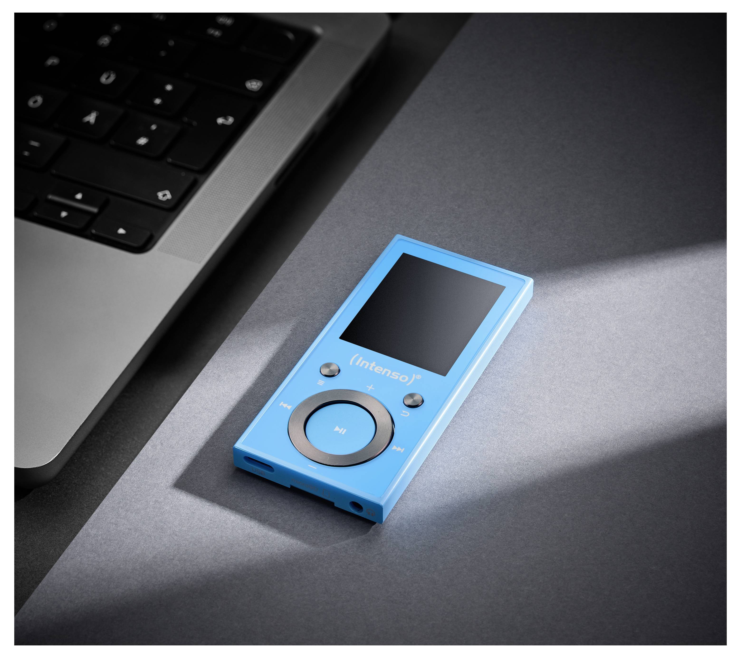 Ein blauer tragbarer Mediaplayer mit einem kreisförmigen Bedienpad und einem kleinen Display liegt neben einer Laptop-Tastatur auf einer grauen Oberfläche.