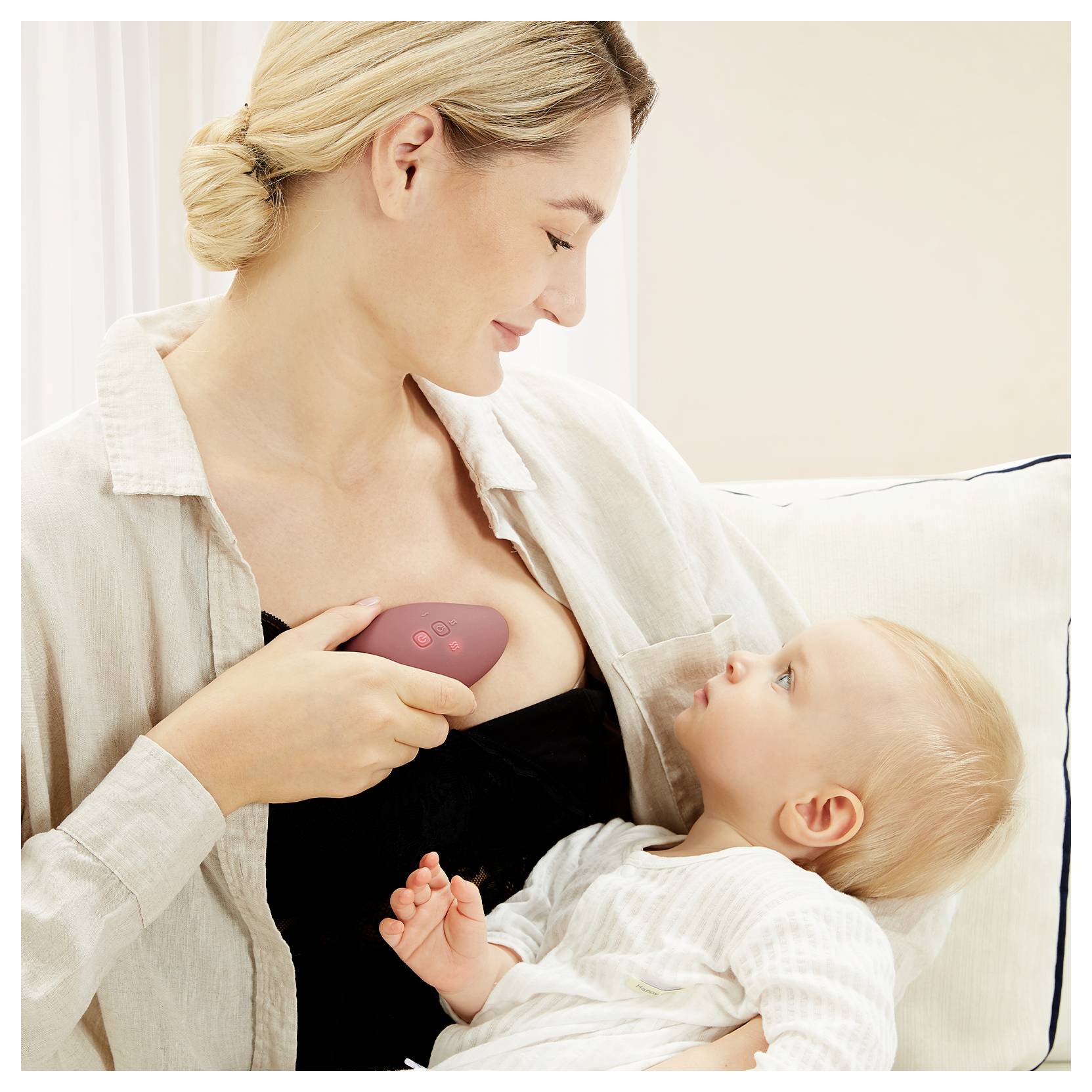 Eine Frau lächelt, während sie eine Milchpumpe an ihrer Brust verwendet und ein Baby auf ihrem Schoß hält. Die Umgebung ist ein weicher, neutral getönter Raum.