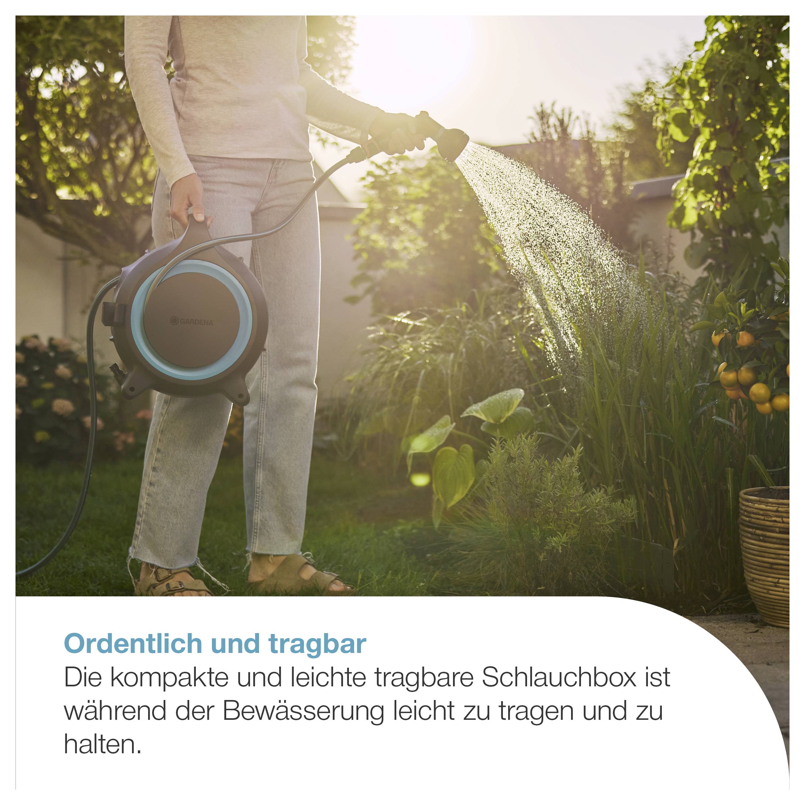 Person gießt im Garten mit tragbarer Schlauchbox; die kompakte, leichte Box ist gut zu tragen und zu halten.<br>