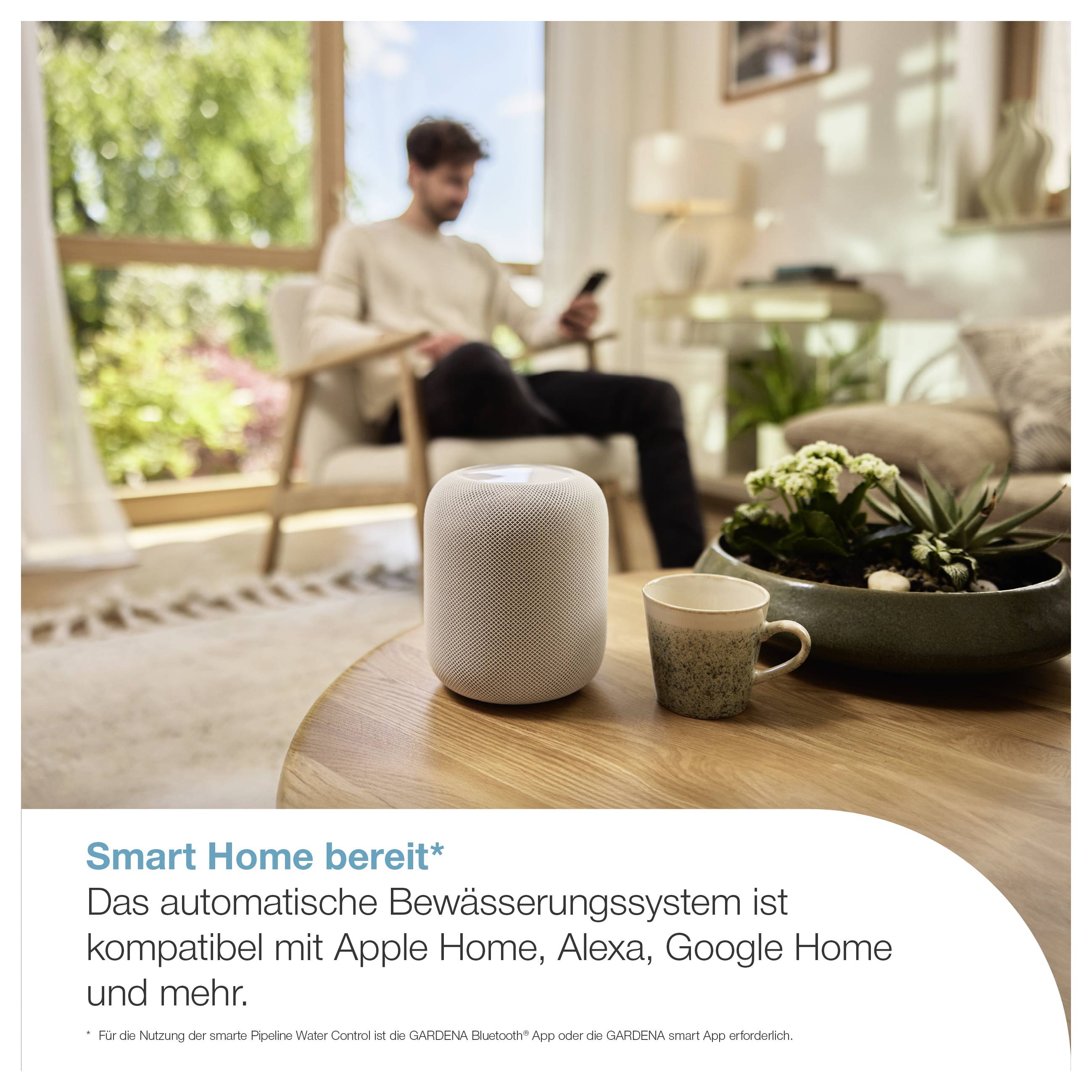 Smart-Home-Bewässerungssystem mit weißem Steuergerät auf einem Tisch; im Hintergrund sitzt ein Mann im Wohnzimmer, Text: 'Smart Home bereit*'.